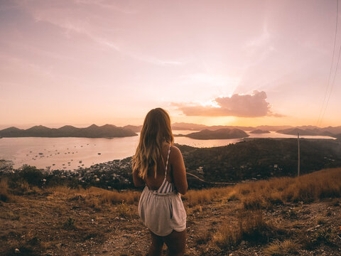 Woman in brown field looking at sunset