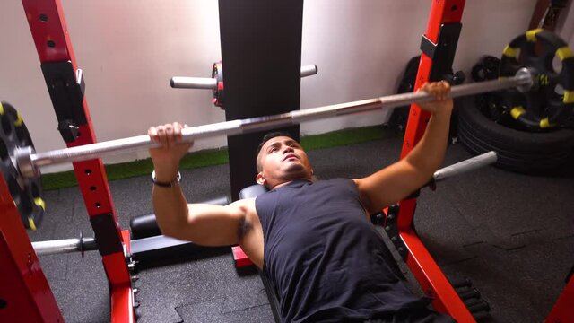 a man (lying down) doing a bench press in his personal gym