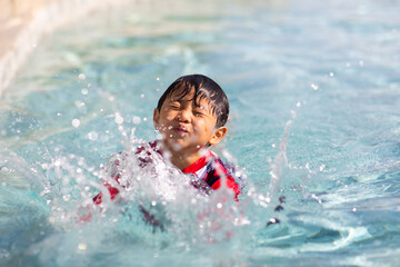 Fototapeta na wymiar Cute Asian boy jumping into underwater at swimming pool.