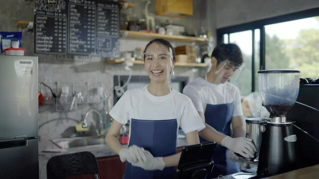 Asian female coffee shop employee The menu is being offered to customers during the COVID epidemic. And new normalcy lifestyle.