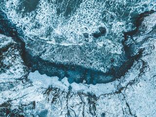 Aerial view of sea waves hitting rock beach