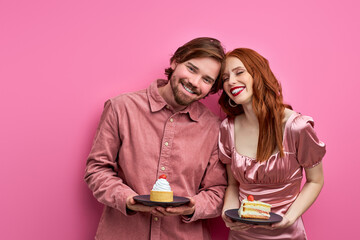 couple is going to celebrate birthday or st valentines day, holding cakes on plate, happy together, smile, wearing party clothes