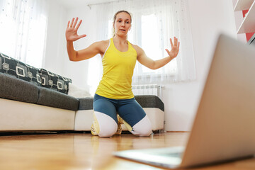 Muscular fit fitness instructor showing online exercises over laptop.