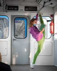 Very flexible woman wearing mask reading book in the subway car sitting in the gymnastic split....