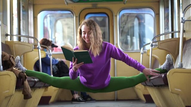 Girl sitting on the split in the subway car and reading book. Concept of education and self-development.