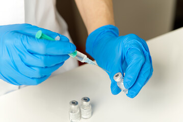 doctor hands injecting a syringe needle into a small bottle with a vaccine or drug assign virus or flu.