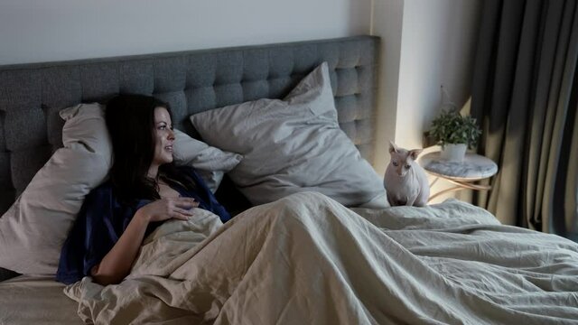 woman and her cat in bed at sunday morning, enjoying and rejoicing by good mood