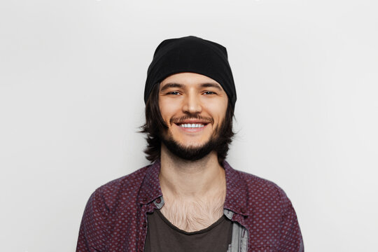 Studio portrait of young smiling  guy with black hat on white background.