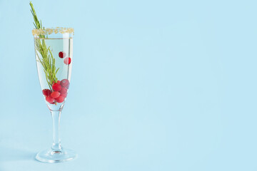 Glass of champagne cocktail with cranberry and rosemary on color background