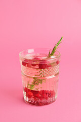 Glass of champagne cocktail with cranberry and rosemary on color background