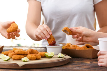 Women eating tasty nuggets with ketchup on table in room
