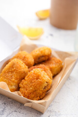 Tasty nuggets in paper box on light background