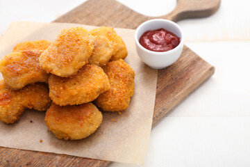 Tasty nuggets with ketchup on light background