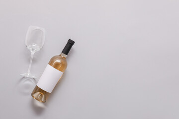 Bottle of wine with blank label and glass on light  background