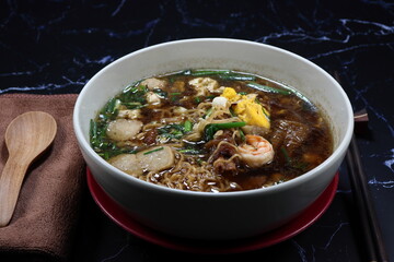 Special hot soup of instant noodle with egg, shrimp ball and mixed vegetable serving in the bowl. Famous comfortable food menu in Asia. 