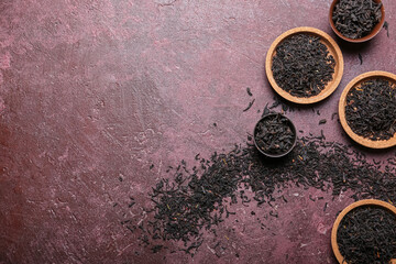 Dry black tea leaves in bowls on color background
