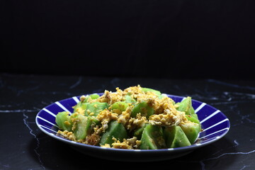 Fried and stirred fresh Chinese zucchini and egg seasoning with pepper and soy sauce serving on the plate. Famous vegetarian menu in Asia restaurant. High fiber and low fat food. 
