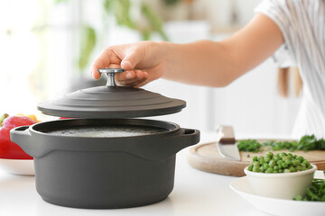 Woman and cooking pot with tasty soup in kitchen