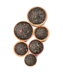 Dry black tea leaves in bowls on white background