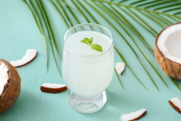 Glass of fresh coconut water on color background