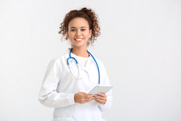 Portrait of female doctor with tablet computer on light background