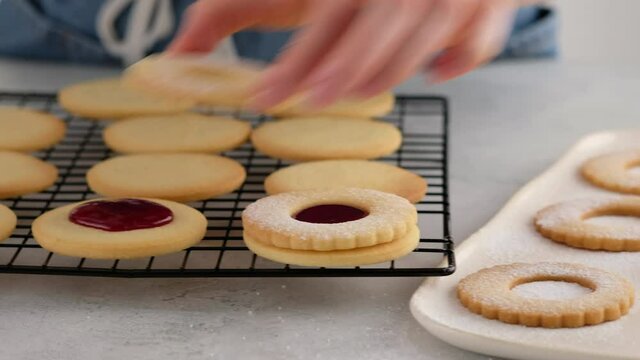 Female hands put cookies on the second cookie with jam. Female hands a making homemade biscuit shortbread cookies with jam. Kurabye cookies with raspberry jam. Christmas cookies with jam.