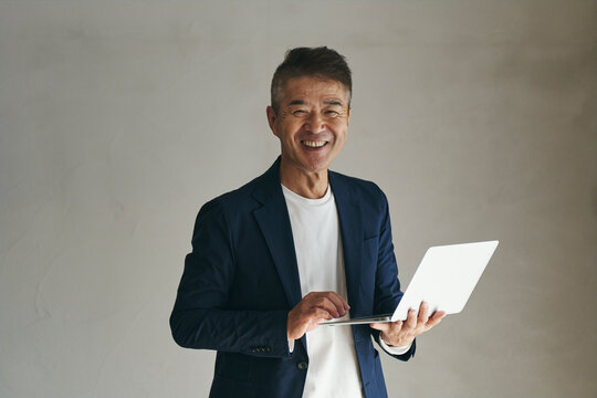 ノートパソコンを持つ日本人シニア男性