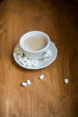 A cup of marshmallow coffee on a brown wooden table