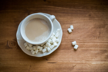 A cup of marshmallow coffee on a brown wooden table