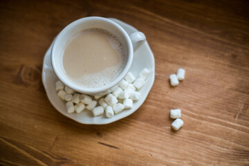 A cup of marshmallow coffee on a brown wooden table