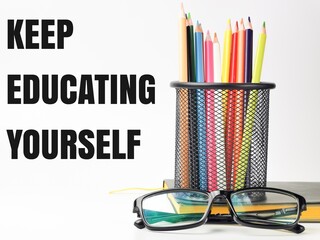 Phrase KEEP EDUCATING YOURSELF on white background with colorful pencil,eye glasses and a...