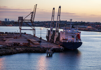 Cargo ship berthed and loading scrap steel in Fremantle Harbour at dawn.