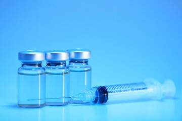 Blue filter light effect of vaccine injection vials medicine drug bottles and syringe. Vaccination, immunization, treatment to cure virus infection. Soft focus image.