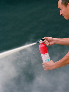 Asian man using fire extinguisher