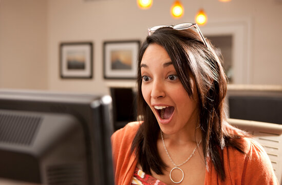 Surprised Hispanic woman using computer