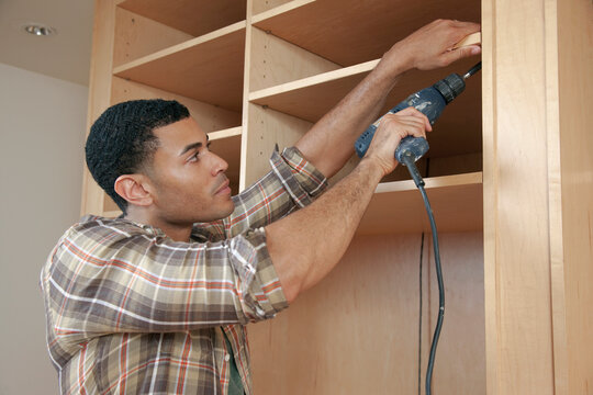 Mixed race man building cabinet