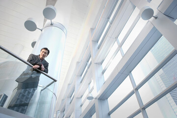 Asian businessman leaning on office railing