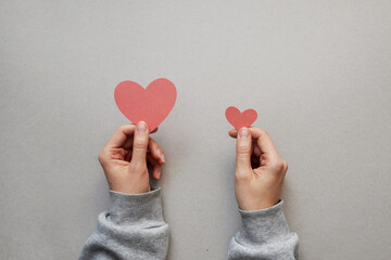 A big pink heart and a small heart in the hands of a person. Big and small love in a person's life