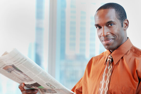 African American businessman reading newspaper in office