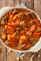Maafe a spicy peanut stew made with beef, sweet potatoes and carrots closeup in the pan on the table. Vertical top view from above