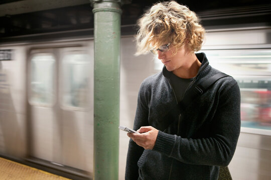 Caucasian man text messaging on cell phone in subway