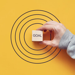 Word: target, in the center of the target on a yellow background. A person wants to achieve a goal....