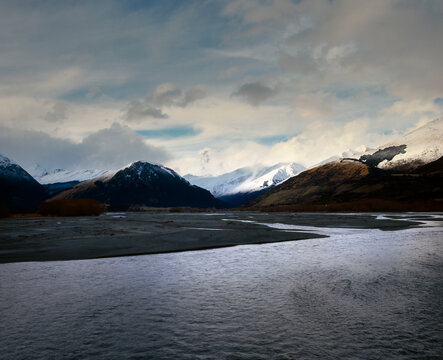 Snow capped mountains line Rees River as it runs into the head of Lake Wakatipu in Glenorchy 