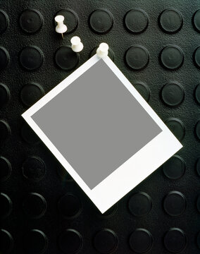 Blank polaroid pinned to rubber pinboard 