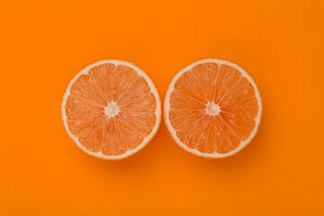 Lemon slices on orange minimal background. Bright juicy lemon on orange blank isolated background. Summer, sun, health concept.
