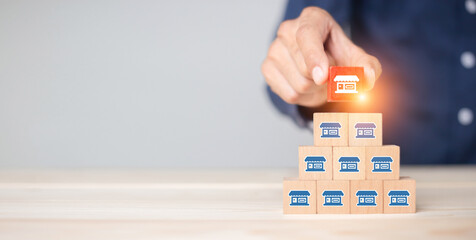 Franchise business,Businessman hand choose wooden blog with franchise marketing icons Store. Franchise business concept.