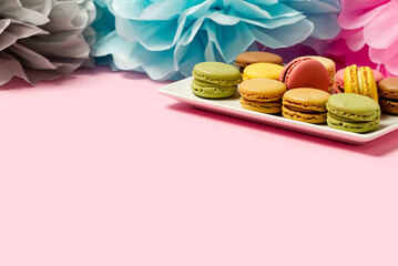 Colorful macarons on the plate on pink background with copy space