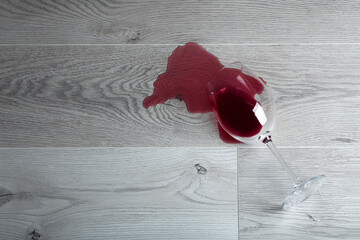Wooden floor with overturned glass of red wine. Spilled wine on a wooden laminate (parquet) floor with moisture protection.