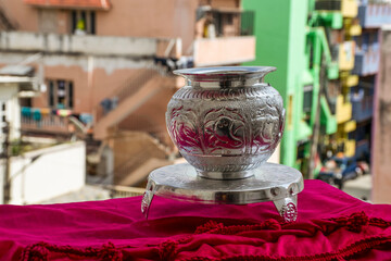 Beautiful carved silver pot or kalash and stand used in hindu rituals, on blur background.