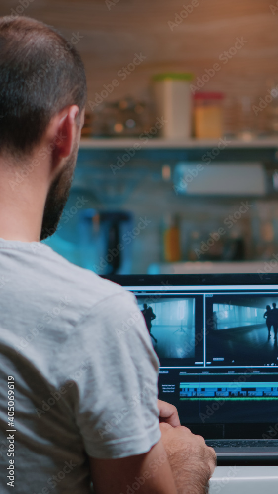 Poster colorist working remotely overtime from home using editing software sitting in front of laptop late 